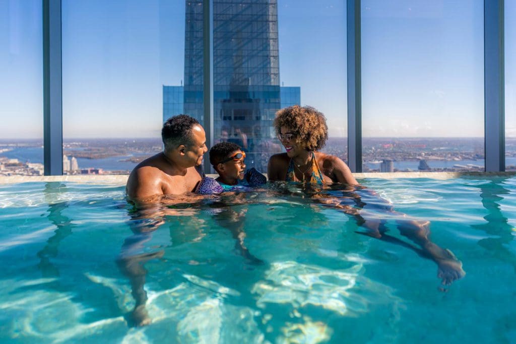 A family of three enjoys the indoor pool, with a sweeping view of downtown Philly, at Four Seasons Hotel Philadelphia at Comcast Center.