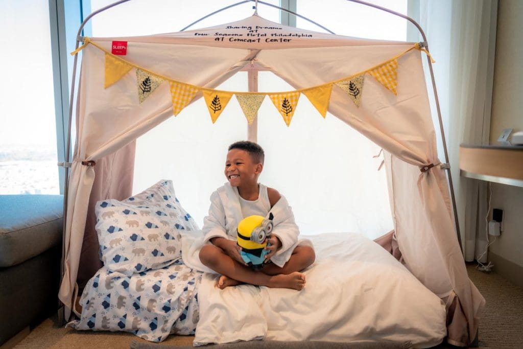A young boy sits in an in-room kids tent, provided by Four Seasons Hotel Philadelphia at Comcast Center.