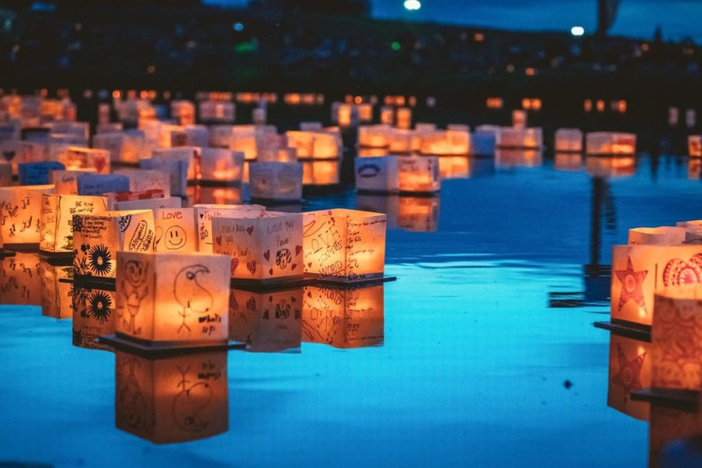 Several lanterns, lit with wishes, float on a pond at the Water Lantern Festival in Temecula.