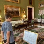 A young boy reads a museum plaque while touring the White House.