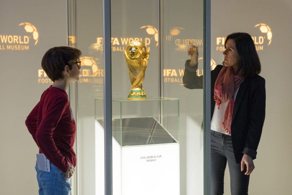 A woman and her young son look at a trophy in a case at the FIFA World Football Museum.