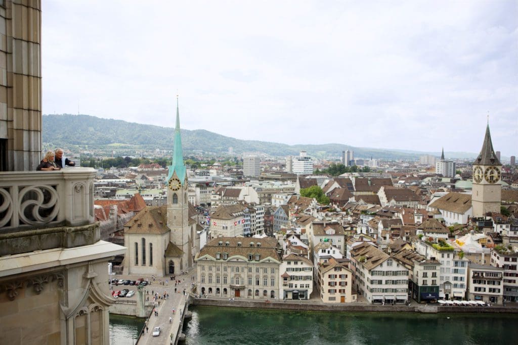 An older couple enjoys a view of Old Zurich from atop a church in the center of the city.