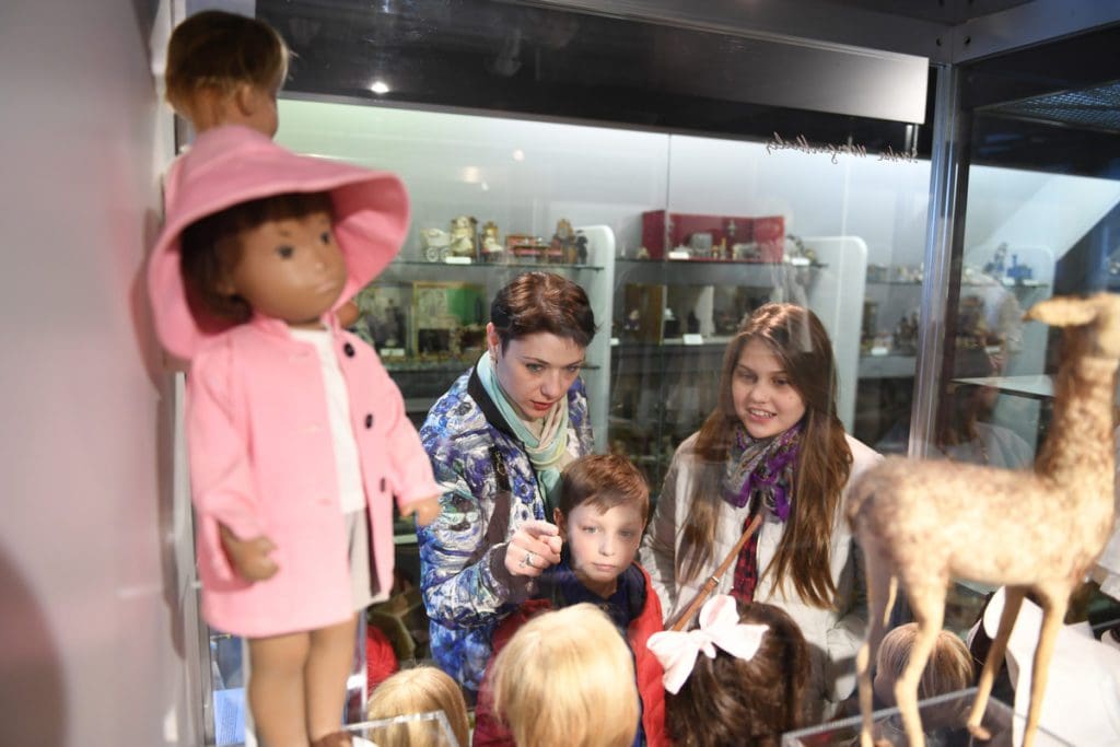 A family looks at dolls in a museum case at Zürcher Spielzeugmuseum. 