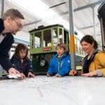 A family of four looks at tram maps at the Zürich Tram Museum.