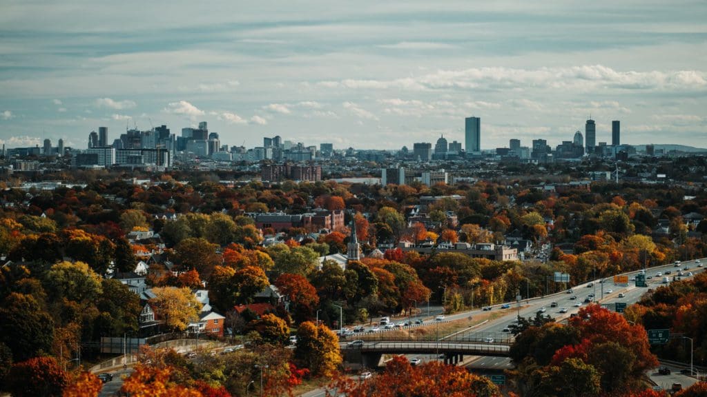 An aerial view of Boston, studded in colorful fall foliage, one of the best places to visit during Thanksgiving with your family in the Northeast.