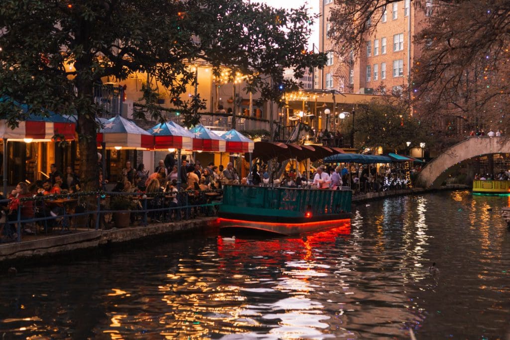 A boat moves through the canal in Alamo Plaza in San Antonio at night.