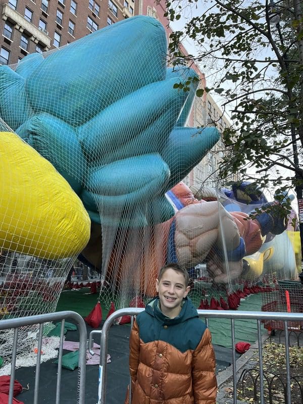A young boy stands in front of parade balloon under the nets at a pre-Marcy's Day Parade event.