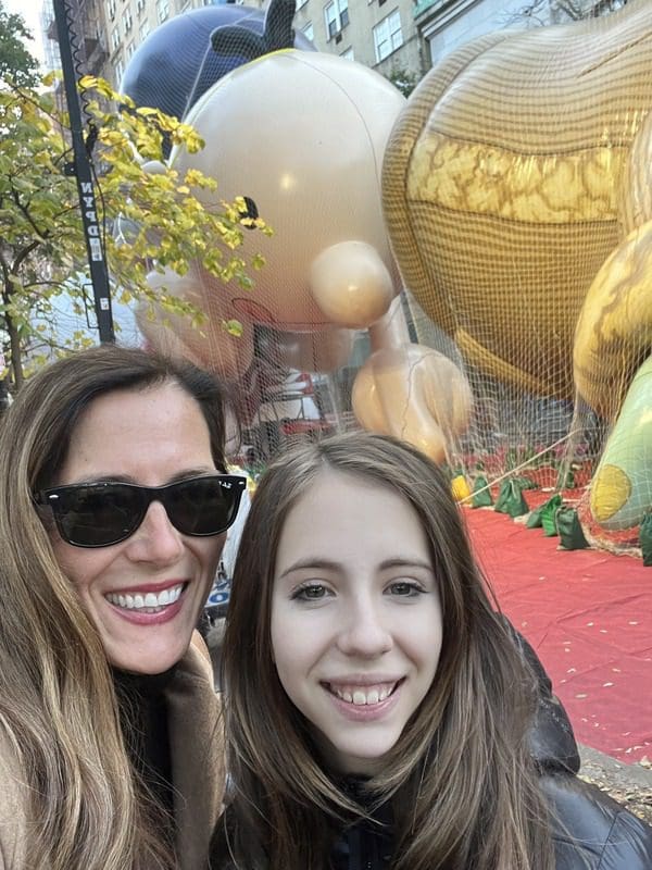 A mom and her daughter take a selfie in front of a parade float.