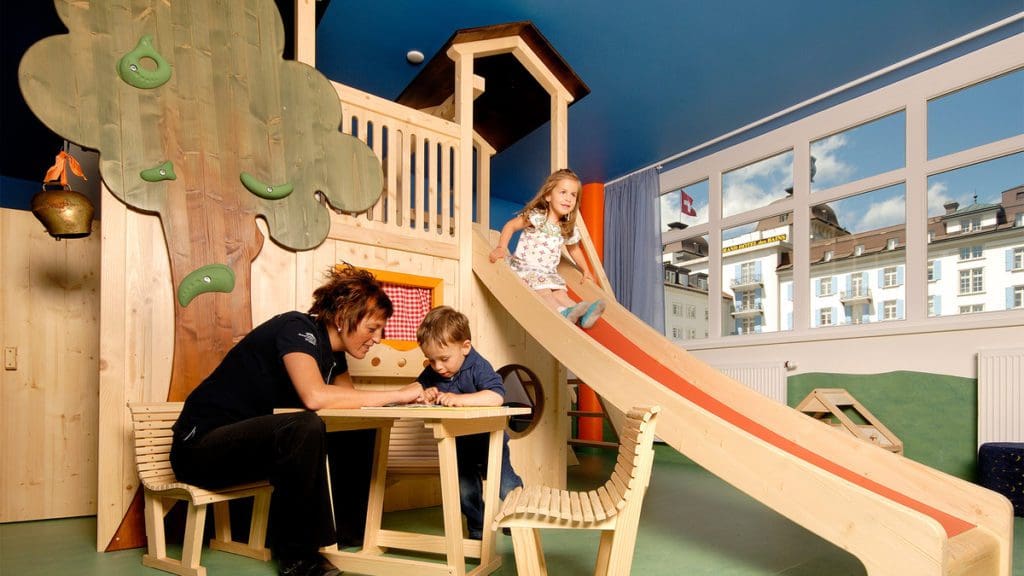 Kids play with a staff member in the kids' club at Grand Hotel Des Bains Kempinski St. Moritz.