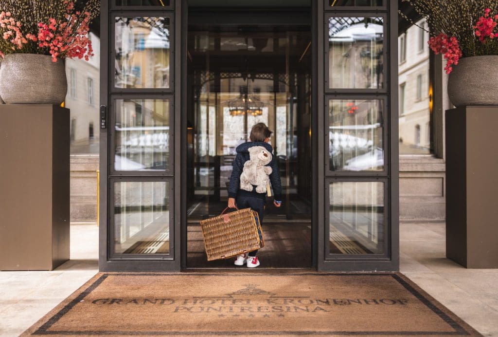A little boy with a suitcase walks into Grand Hotel Kronenhof.