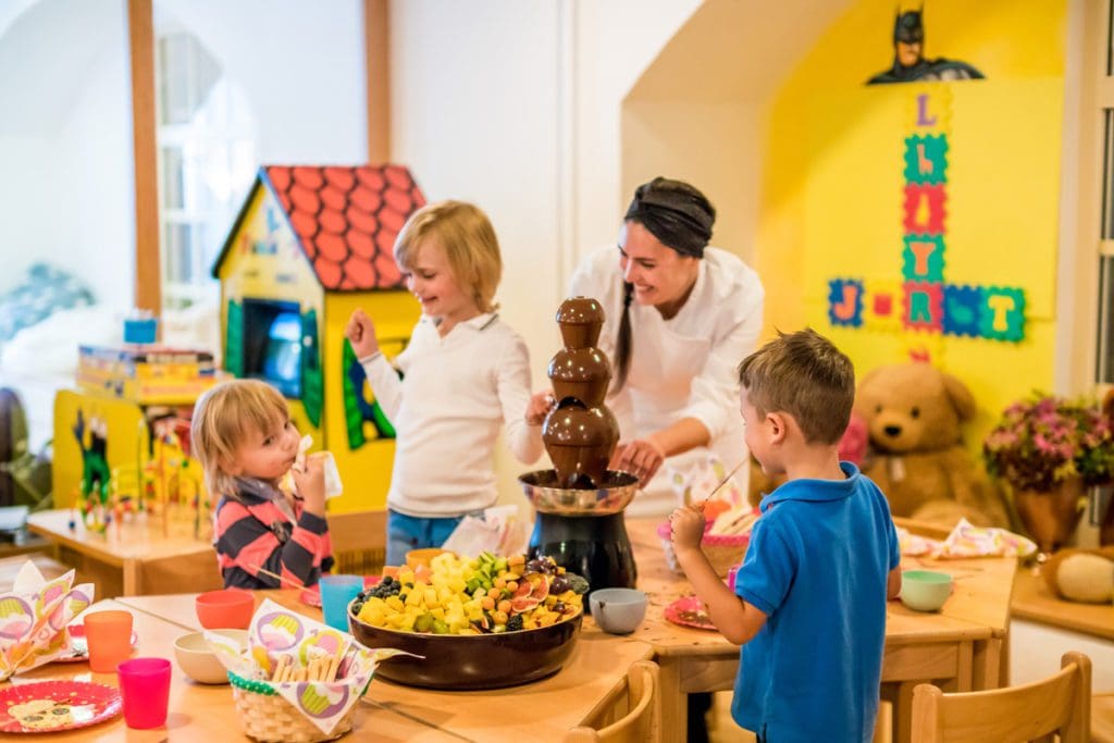 Kids play with a staff member in the colorful kids' club of Grand Hotel Kronenhof.