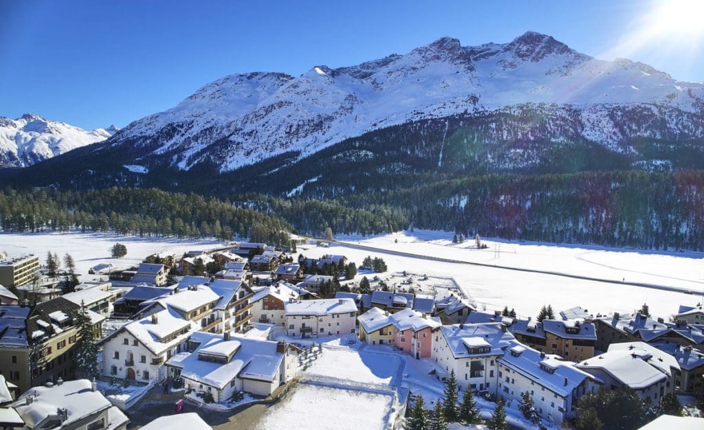 An aerial view of Hotel Giardino Mountain against the mountains in the snow.