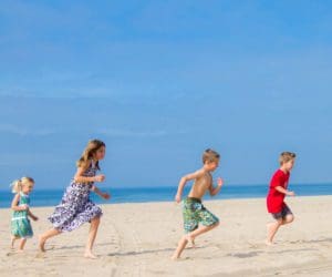 Kids race across a beach, flying kites, while staying at Hyatt Regency Huntington Beach Resort, one of the best hotels in Los Angeles for families.