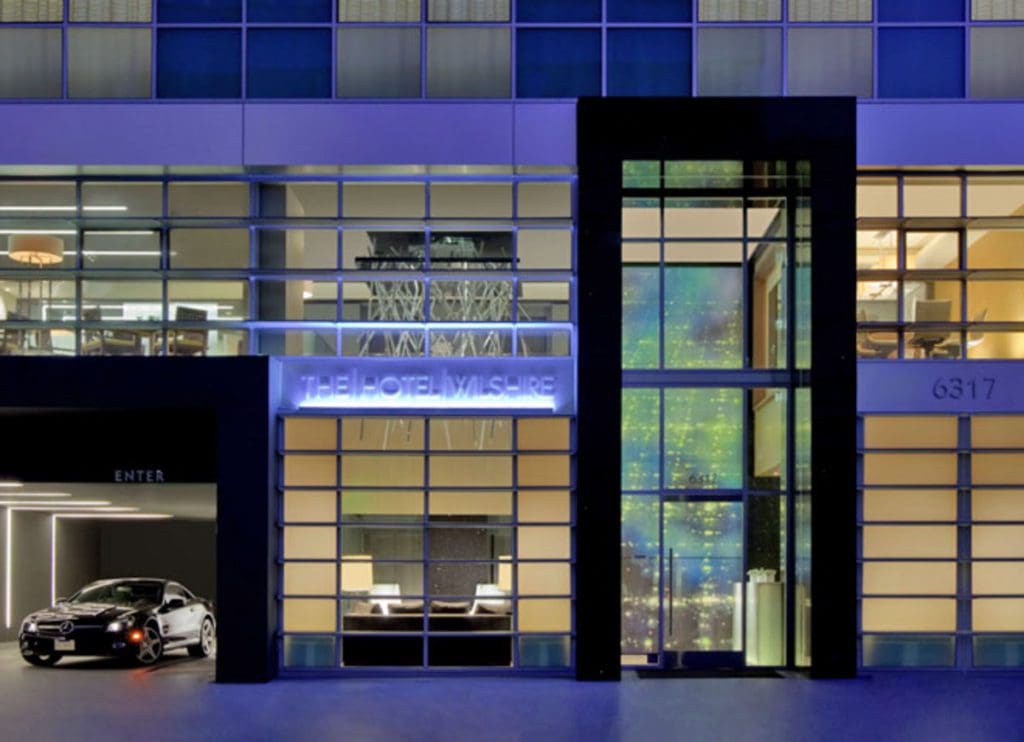 The entrance to Kimpton Hotel Wilshire, well lit at night, one of the best hotels in Los Angeles for families.