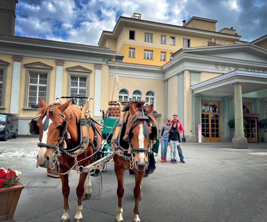 Horse and carriage in front go the Hotel Kulm St Moritz, a must stay in our St Moritz Itinerary with kids.