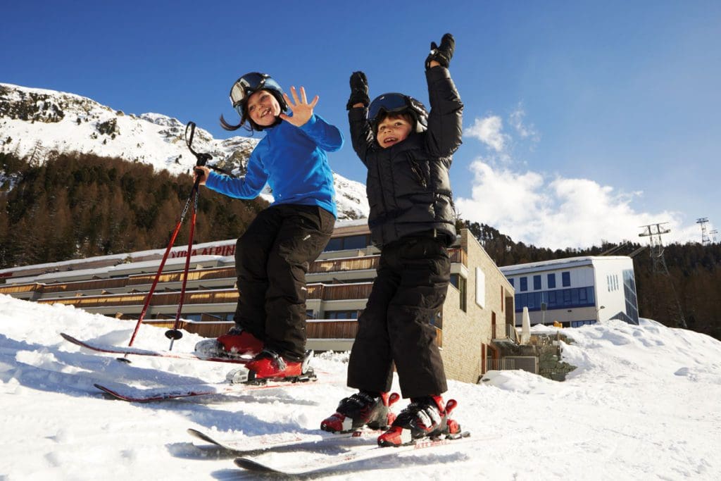 Two kids cheer as they ski near Nira Alpina.
