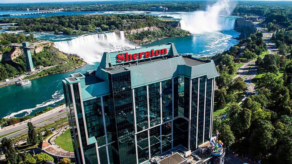 An aerial view of Sheraton Fallsview Hotel, with Niagara Falls behind it.