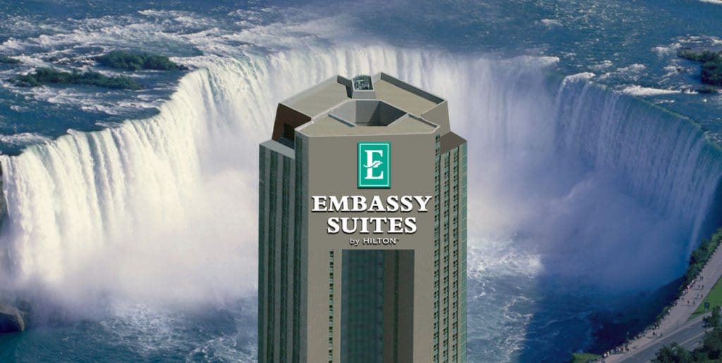 The towering Embassy Suites by Hilton Niagara Falls Fallsview, with a view of the falls behind it.