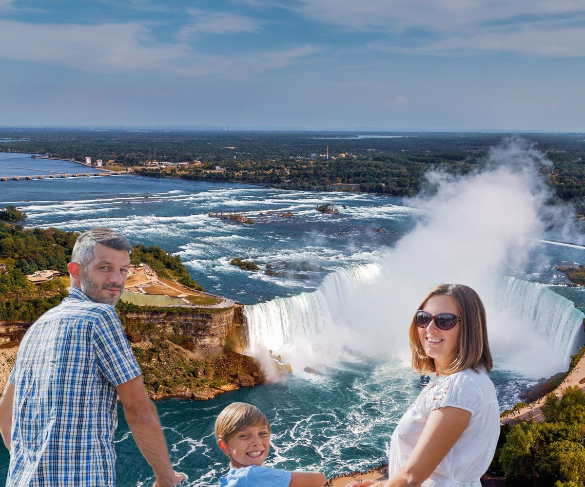 A family of three turns around to smile, with Niagara Falls in the distance.