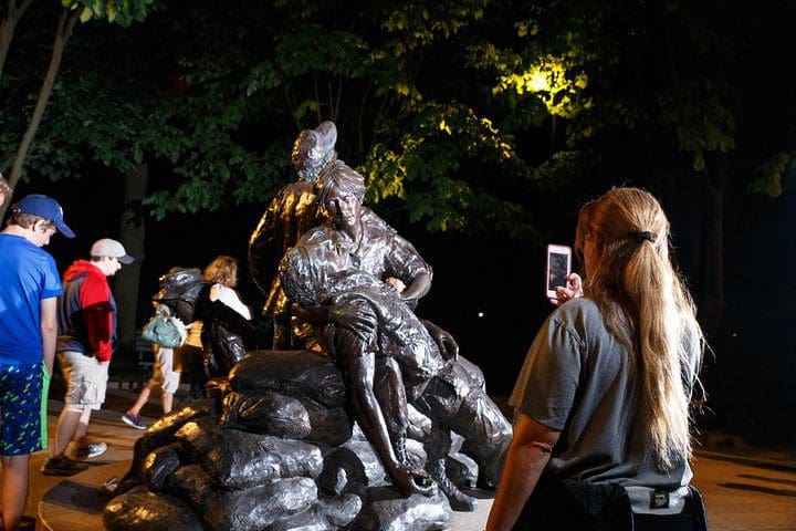 A woman takes a picture of a statue on the DC Monuments and Memorials Night Tour.
