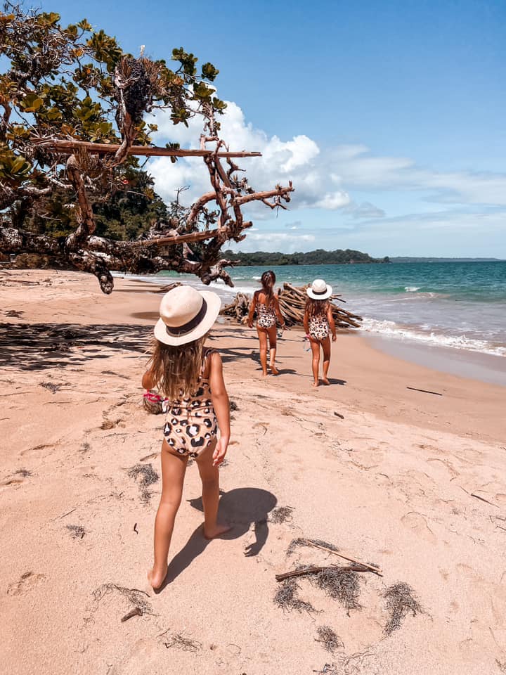 Three young girls walk along a beach in Panama.