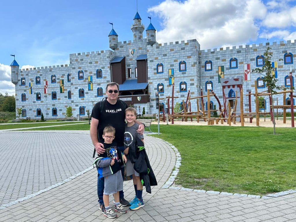 A dad and his young boys stand outside Castle Hotel at LEGOLAND® Billund Resort.