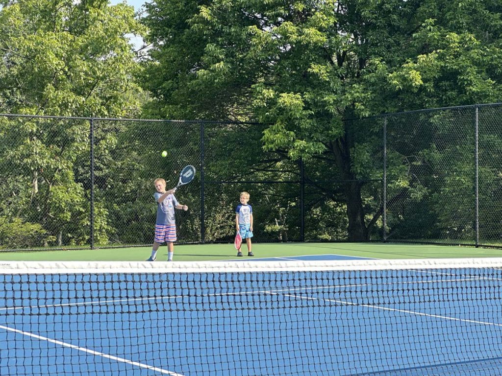 Two boys play tennis at Nemacolin, a family resort in Pennsylvania your family will love.