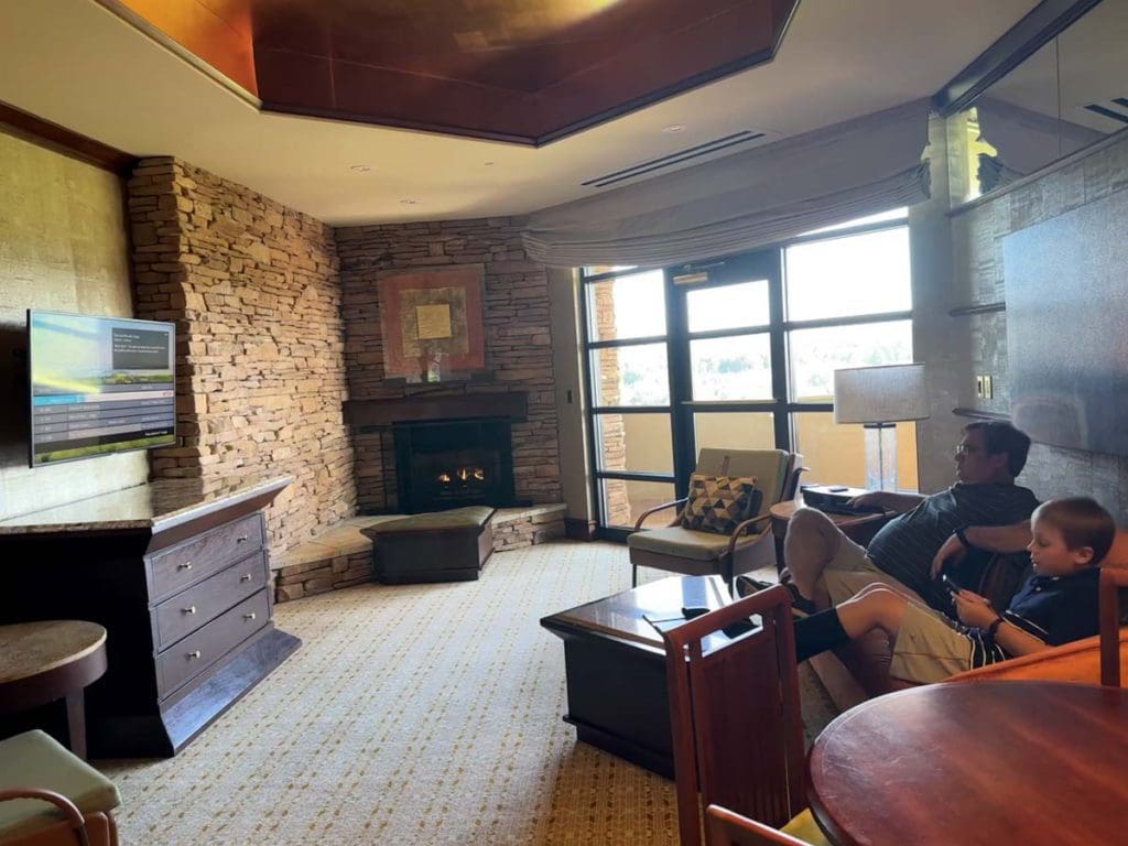 A dad and his young sons enjoy a living room, as part of their accommodations at Nemacolin.