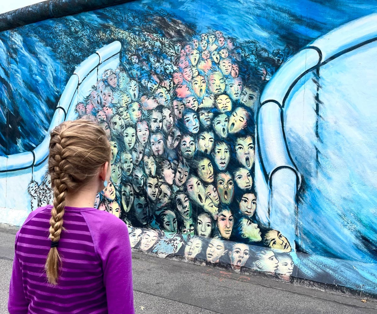 A young girl looks at a mural in East Berlin.