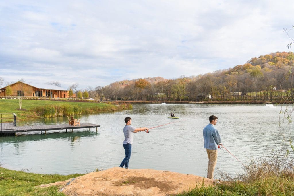 Two teens fish on the lake shore, while staying at Southall Farm & Inn.
