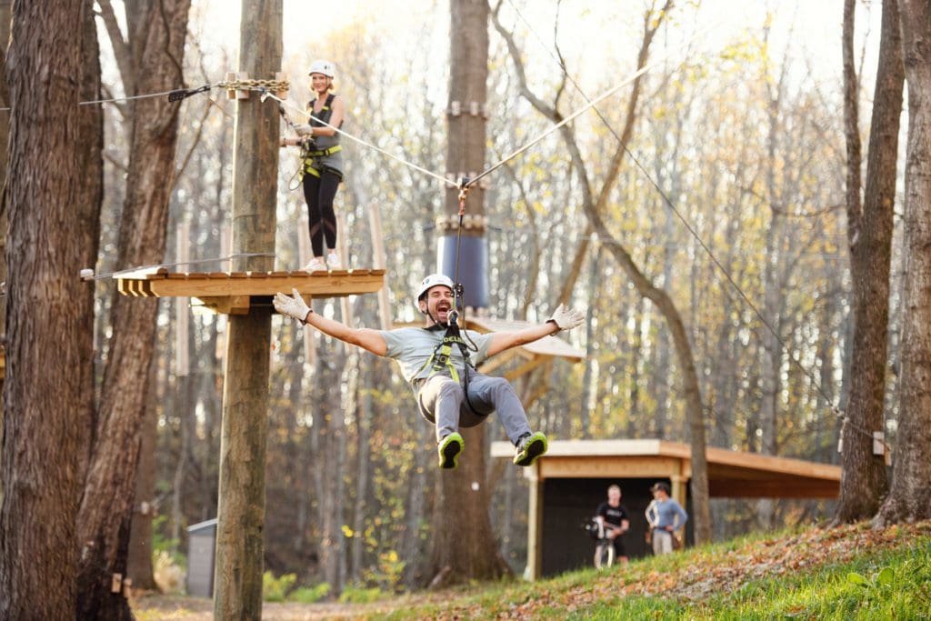 A man ziplines through the trees at the on-site ropes course at Southall Farm & Inn.