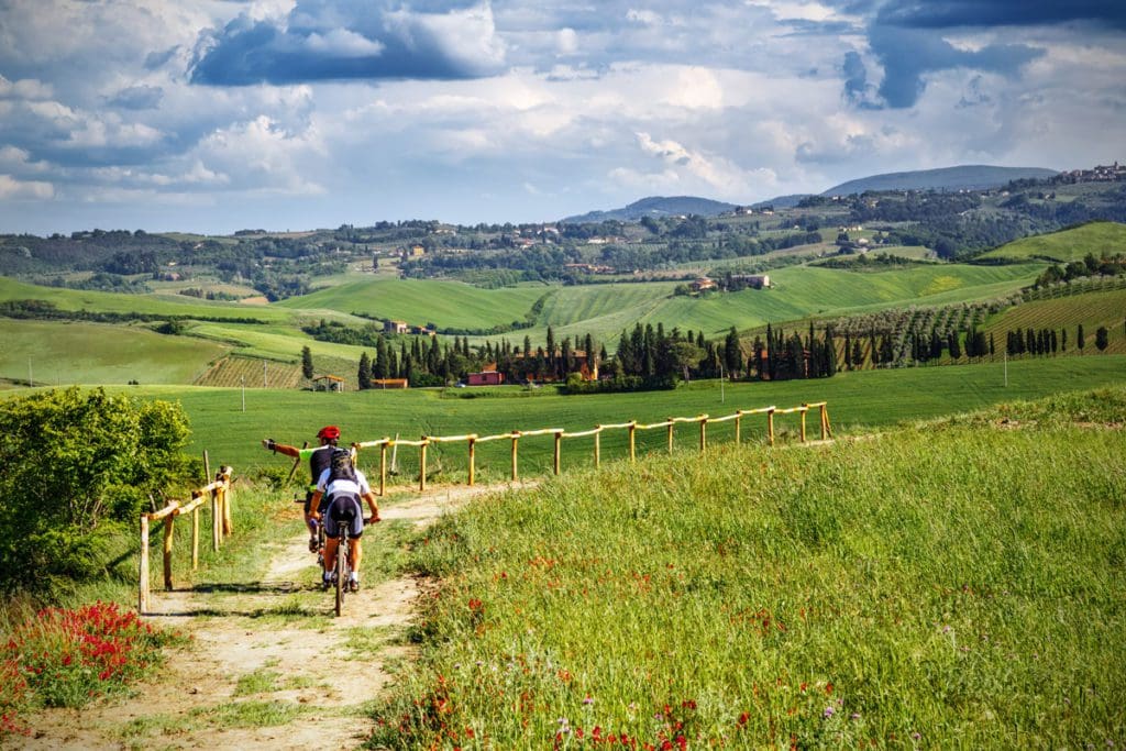 Two people bike in the Tuscan countryside on one of the best tours and classes in Tuscany with kids.