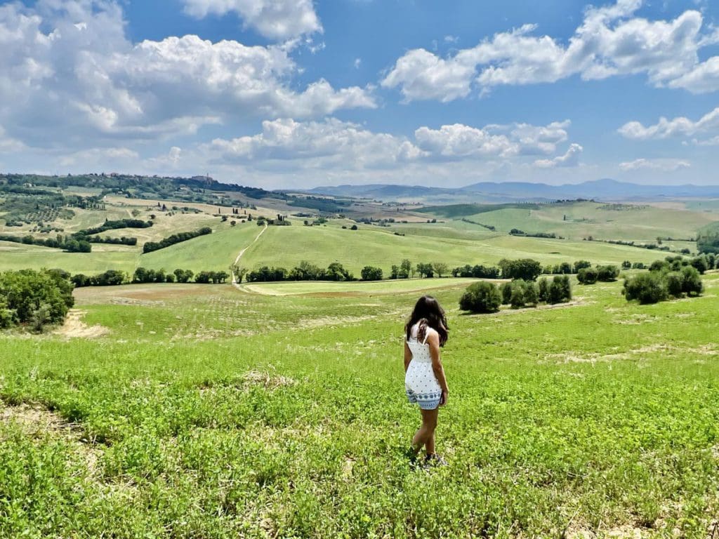 A young girl walks through the rolling hills of Tuscany.