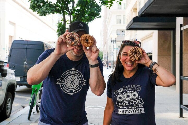 Two people pose with donuts on the Underground Donut Tour: Washington DC Historic Donut Tour.