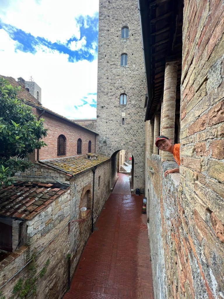 A young boy leans out the window of a historic castle, while on a walking tour in Tuscany.