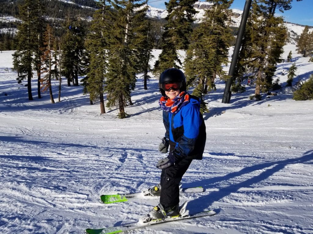 A young boy skis along a slope in Lake Tahoe, while on a ski vacation to Lake Tahoe with kids.