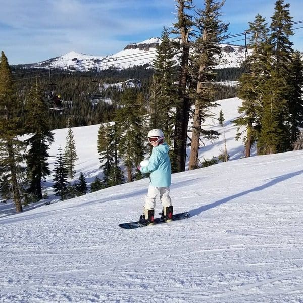A young girl snowboards down a run in Lake Tahoe.