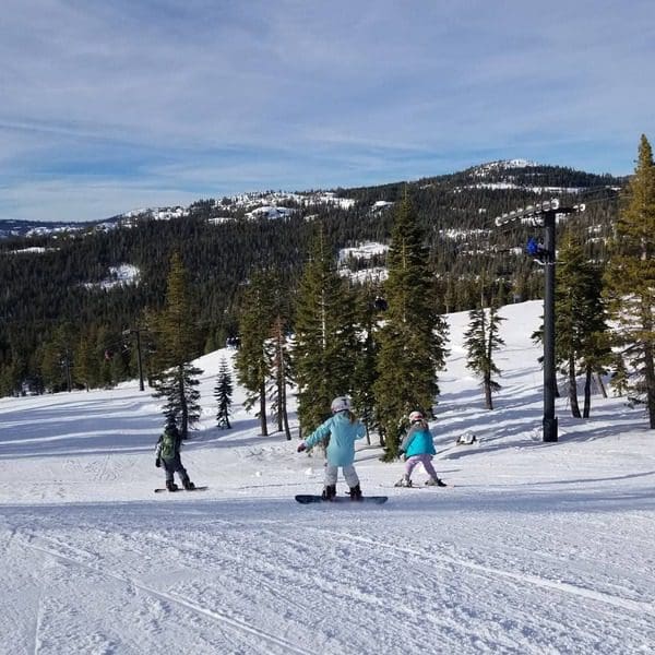 Three kids snowboard down a run in Lake Tahoe.