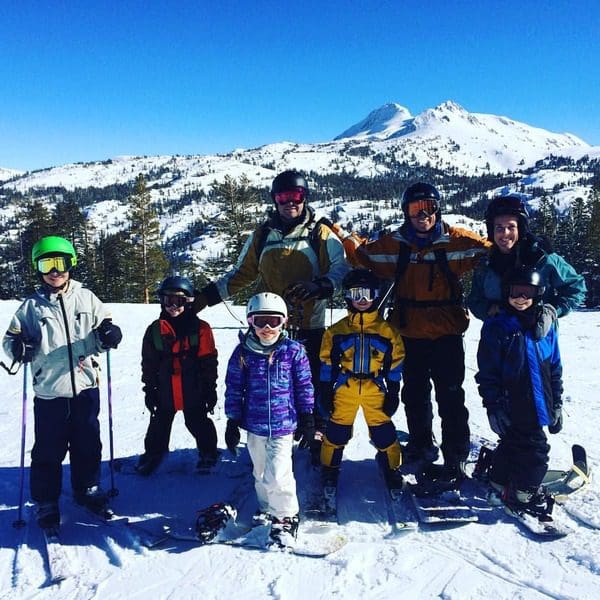 A large group of skiers, including children, stand together while enjoying a day in Kirkwood at Lake Tahoe, while on a ski vacation to Lake Tahoe with kids.
