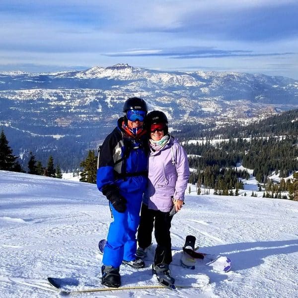 A couple stands together atop a run at SugarBowl in Lake Tahoe, while on a ski vacation to Lake Tahoe with kids.