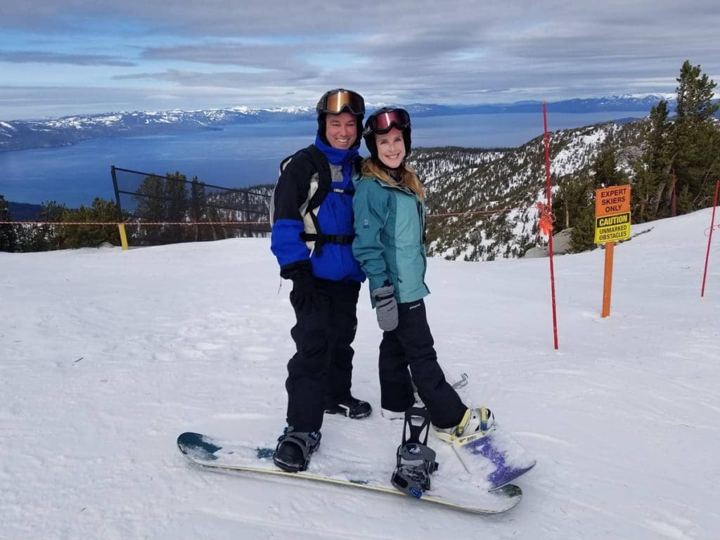A couple stands together atop a run at Heavenly Resort in Lake Tahoe, while on a ski vacation to Lake Tahoe with kids.