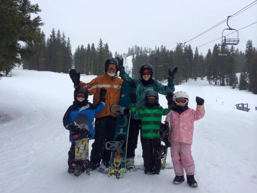 A family of skiers stands together on a snowy ski day in Lake Tahoe.