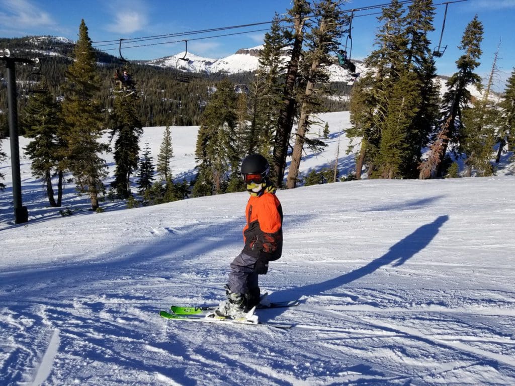 A teen snowboards down a slope in Lake Tahoe, while on a ski vacation to Lake Tahoe with kids.