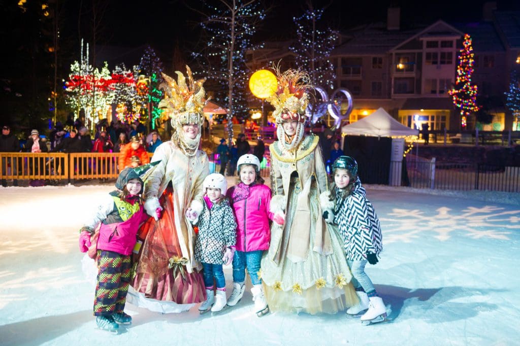 Four kids stand with colorful characters on ice in Whistler.