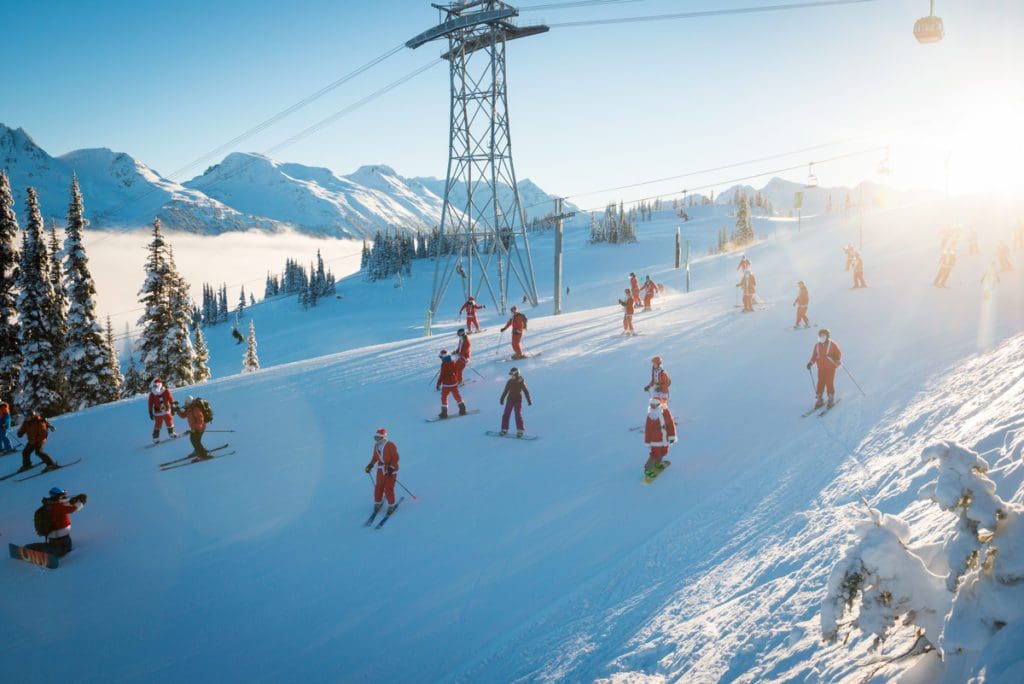 Several Santas ski down a slope in snowy Whistler, one of the best places for Christmas for families in the world.