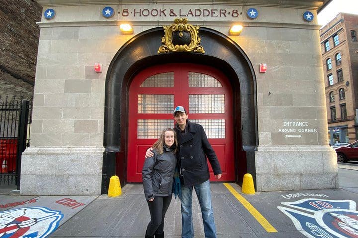 Two people stand in front of an iconic firehouse from a TV show in NYC on the NYC TV & Movie Tour.