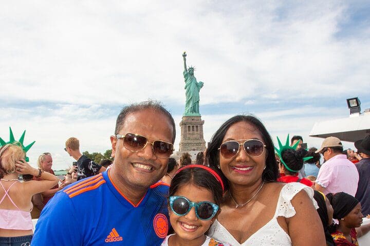A family of three takes a selfie in front of the Stature of Liberty on the New York City Freedom Liberty Cruise.