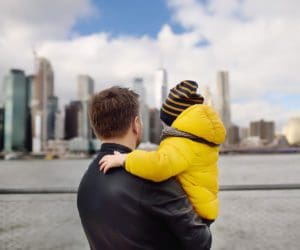 A dad and his young son look out onto a New York City skyline.