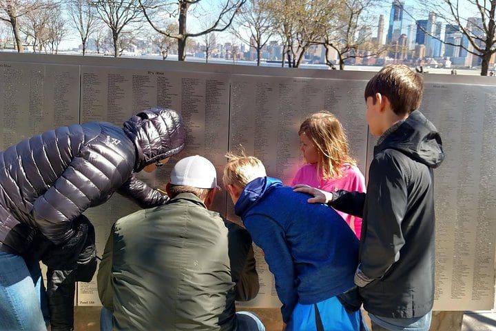 A family explores names on the Ellis Island exhibit, while on the Private Statue of Liberty and Ellis Island Tour.