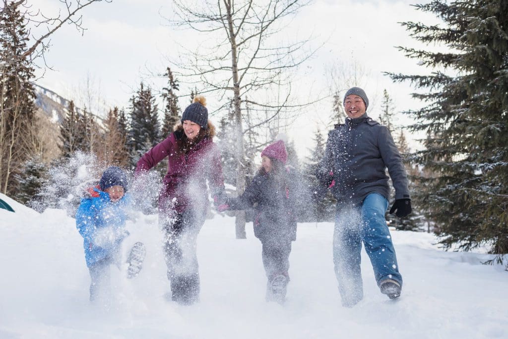 A family of four plays in the snow near Banff, one of the best places for Christmas for families in the world.